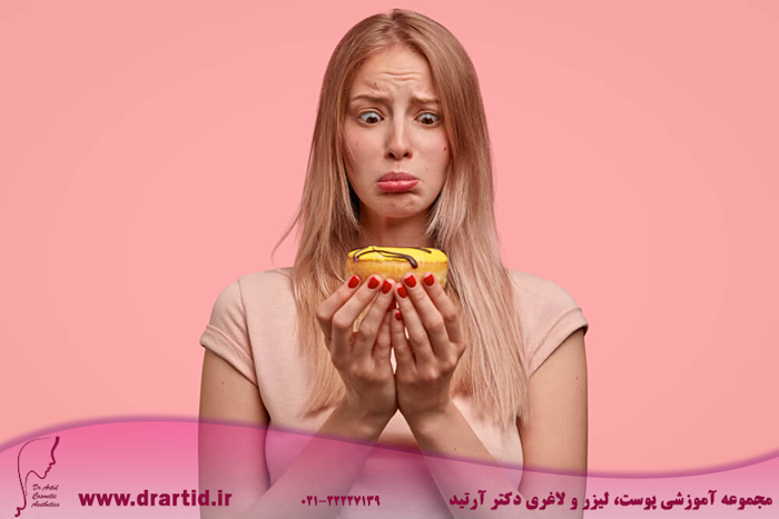 discontent blonde female holds sweet doughnut looks with temptation wants eat keeps diet dressed casual t shirt isolated pink wall people junk food concept - چگونه می‌توانم وزن کم کنم؟