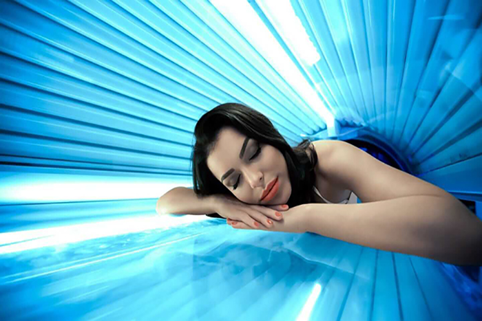 Young woman undergoing tanning skin treatment in solarium - مقالات